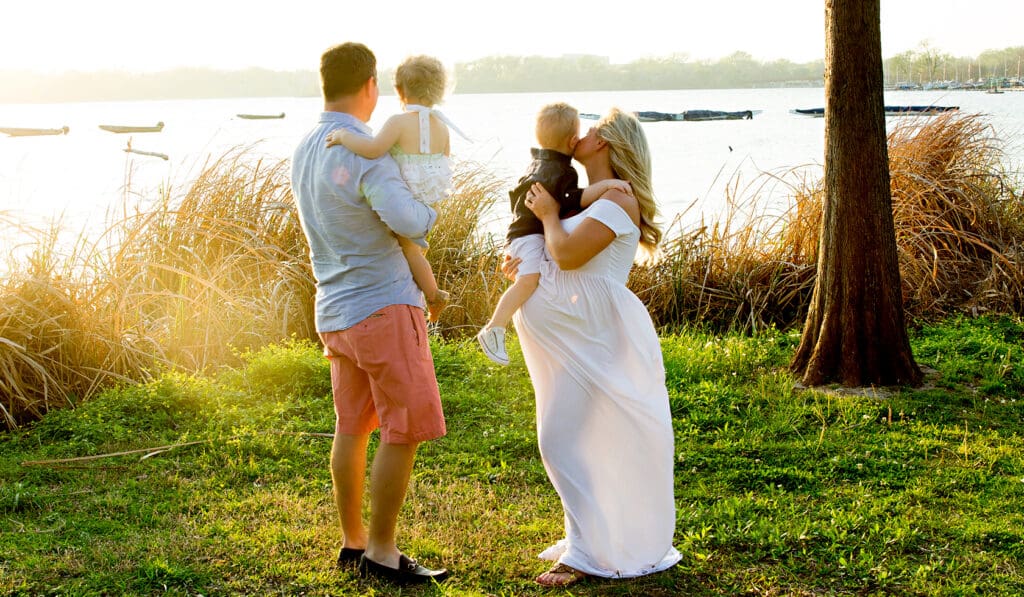 Family expecting a baby are standing next to lake