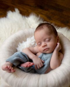 A baby sleeping in a basket covered in white flannel