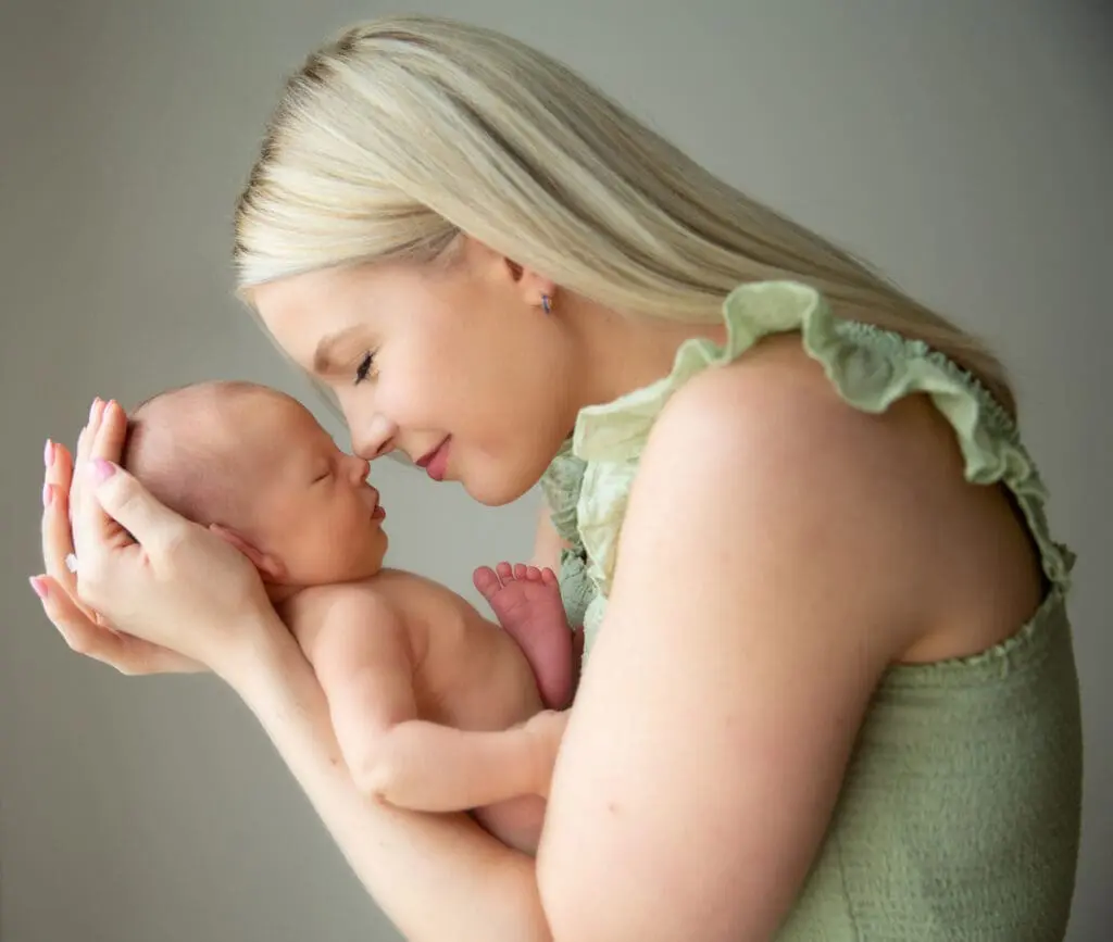 A woman in green dress hollding a baby in her arms